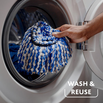 Blue and white microfiber mop head in washing machine drum with hand holding it