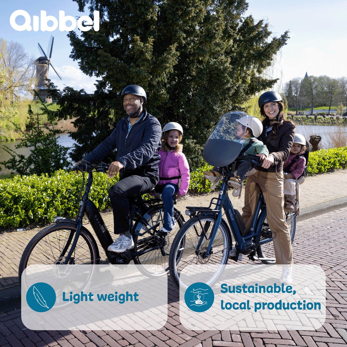 Qibbel Junior black rear bike child seat with two children and adults on bicycle near windmill
