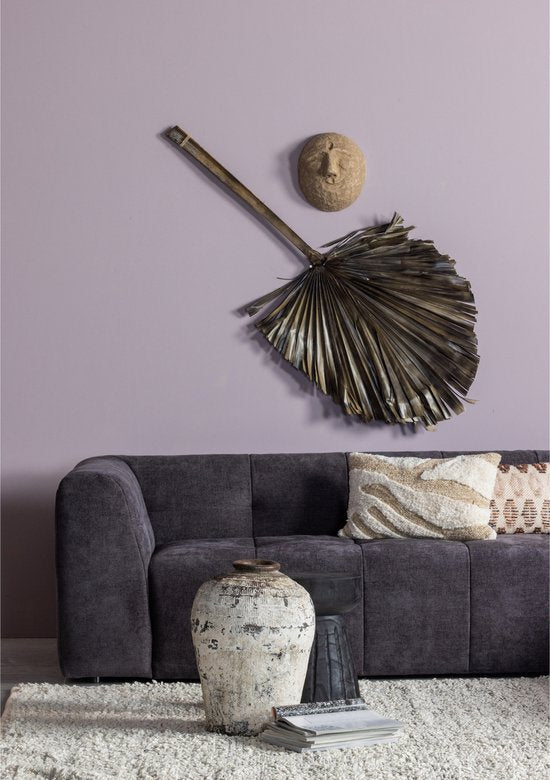 Black palm frond wall hanging and woven sphere above charcoal sofa with decorative accessories