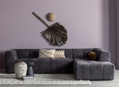 Dark grey modular sectional sofa with black palm leaf wall art and decorative accessories