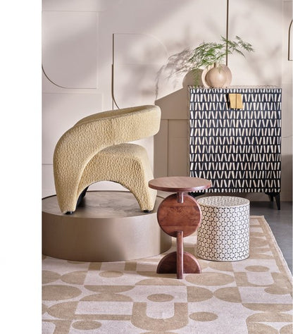 Cream boucle curved accent chair with wooden side table and patterned storage cabinet in modern interior setting