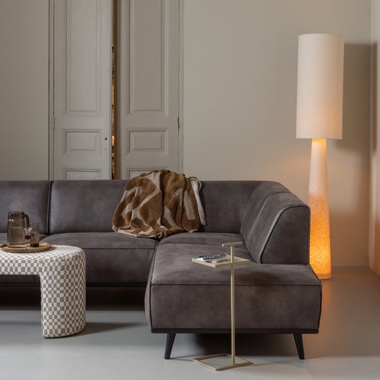 Dark grey leather sectional sofa with gold throw blanket and cylindrical floor lamp