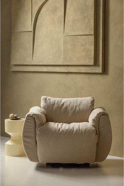 Cream upholstered armchair with rolled arms and cylindrical legs beside yellow metal side table