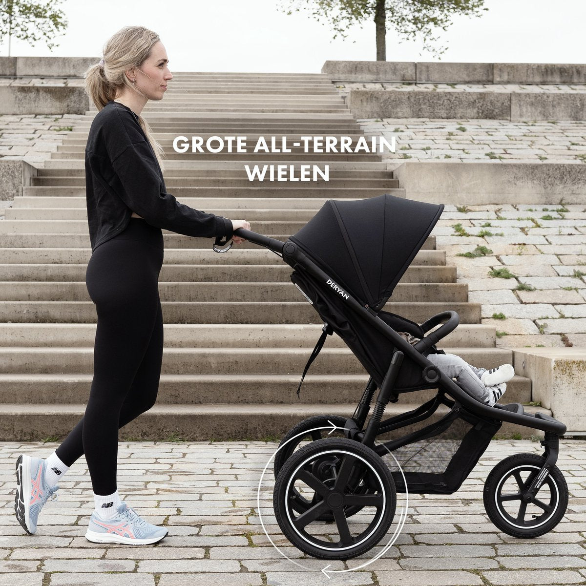 Deryan Bolt black jogging buggy with all-terrain wheels on stone steps
