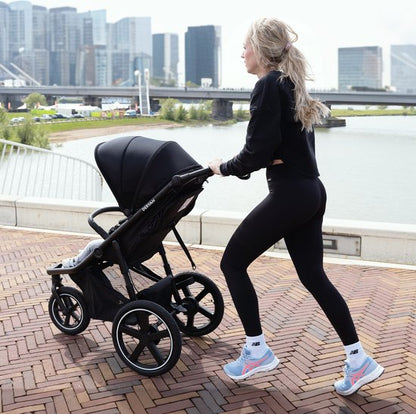 Deryan Bolt jogging stroller in black with three-wheel design being pushed