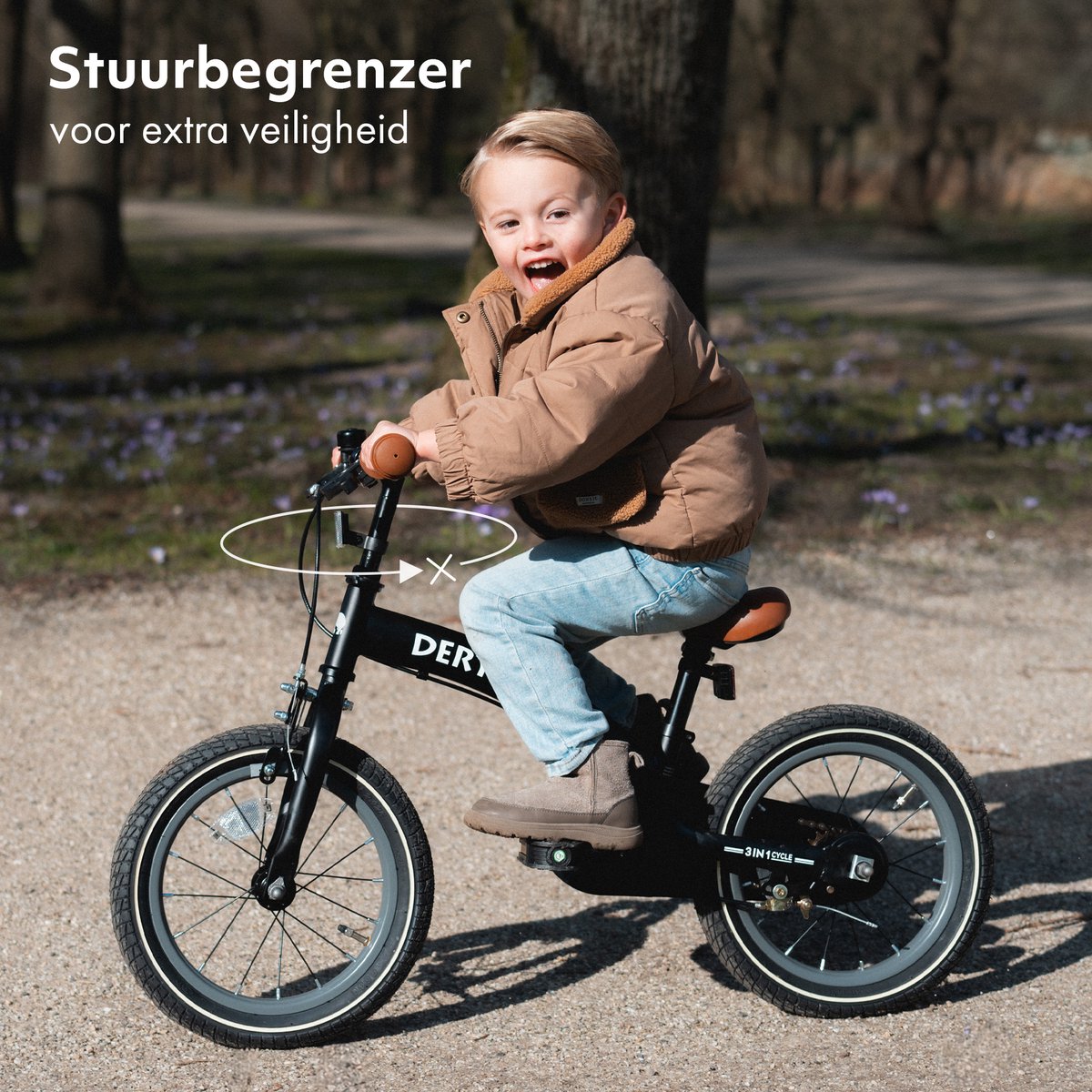 Child riding black Deryan Luxe 12-inch balance bike on path with flowers
